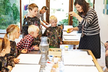 Teacher demonstrating modern painting techniques while students watch.