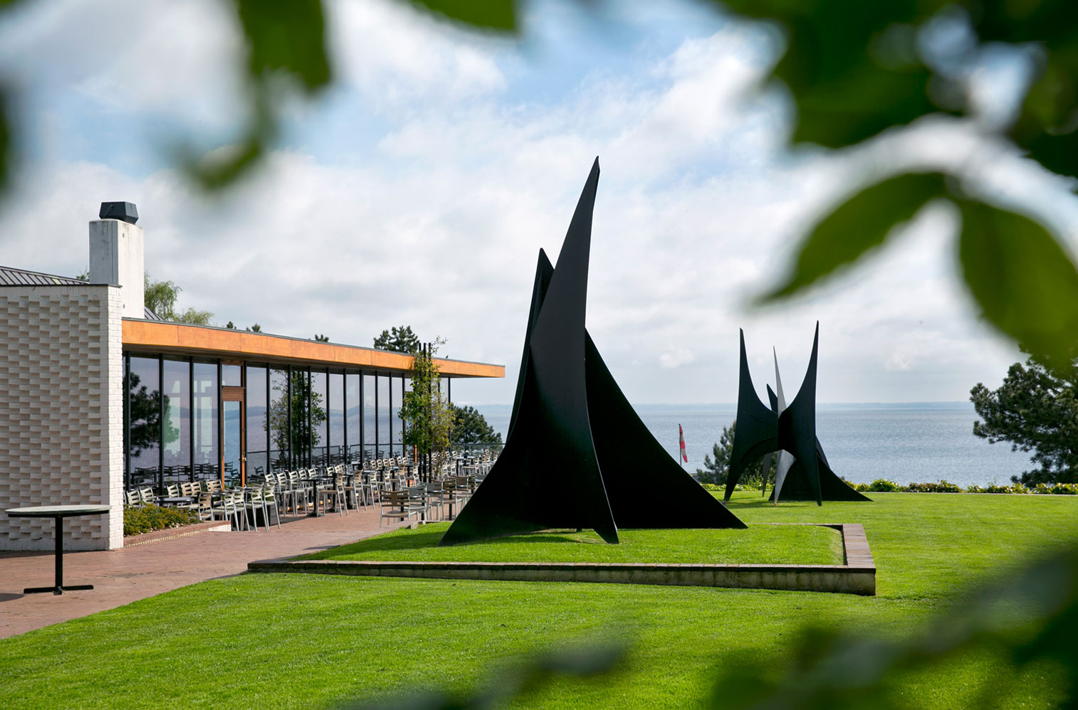 Modern sculpture on the lawn with the Louisiana Museum café on the left.