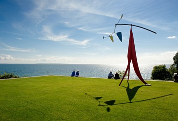 Louisiana Museum sculpture on a green lawn with the sea in the background.