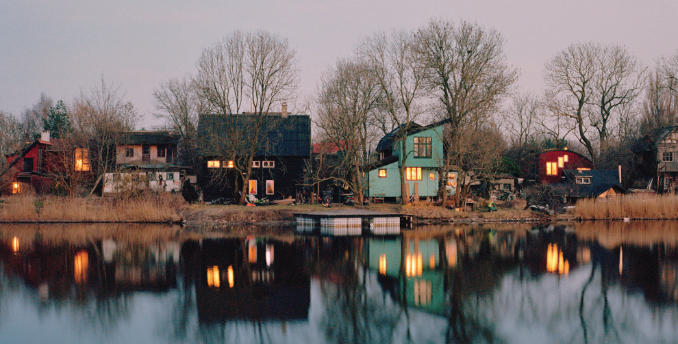Calm canal in Christianshavn with modern houses reflected in still water on a grey day.