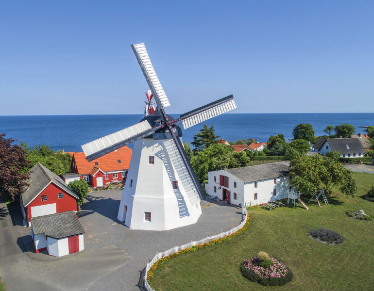Classic white windmill in a courtyard overlooking the sea.