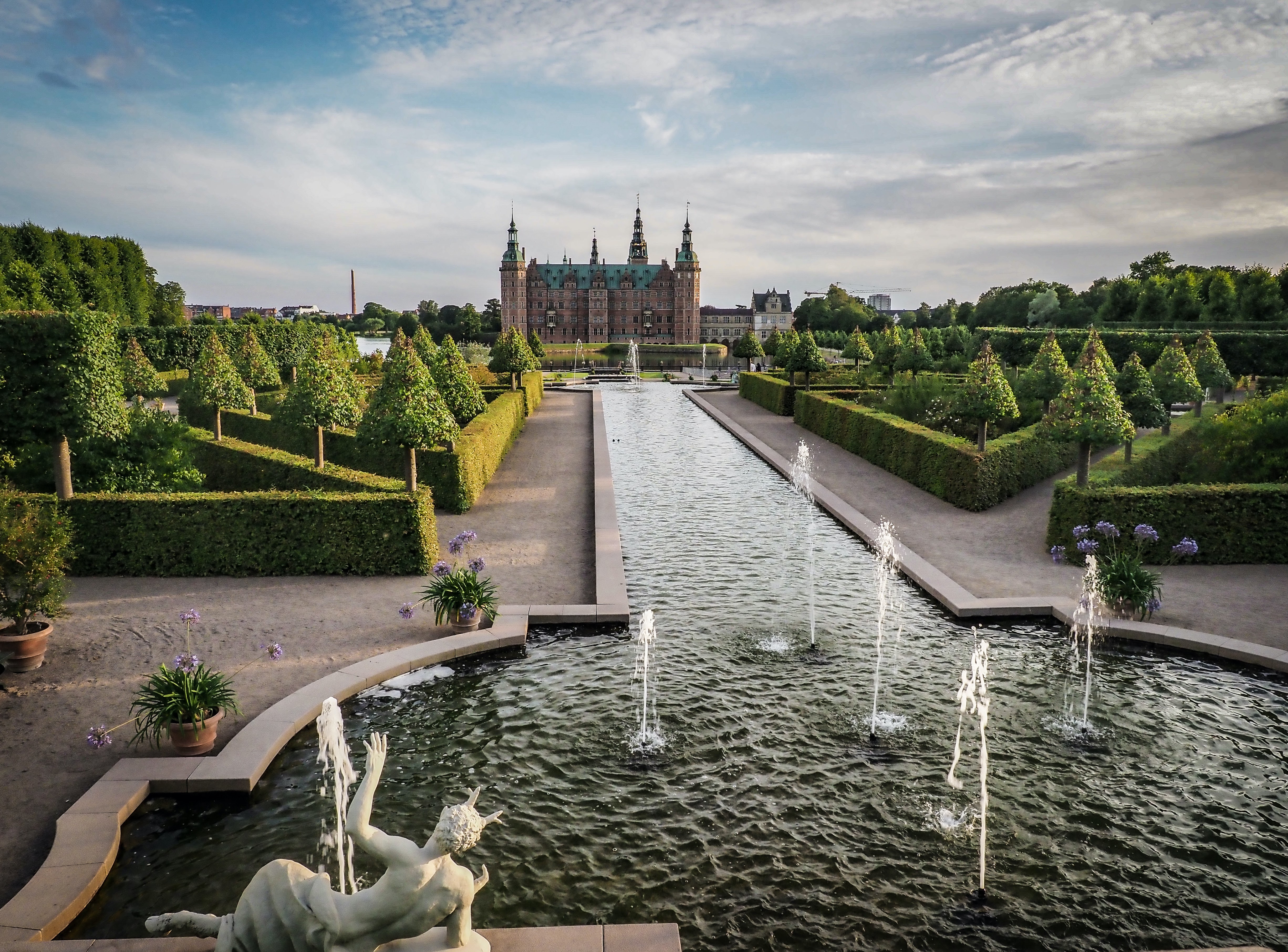 Fountain with long water stream leading to Frederiksborg Castle, flanked by the castle’s courtyard wings.